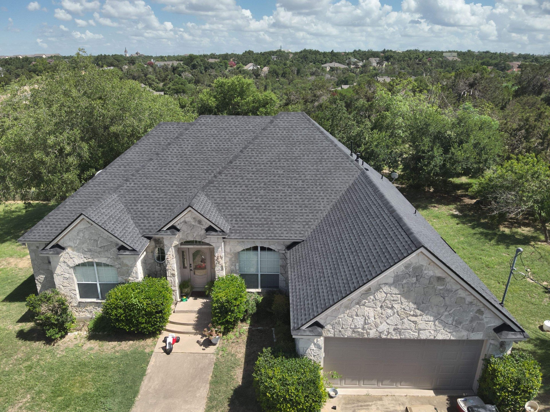 Completed asphalt shingle roof replacement on a stone Tulsa home