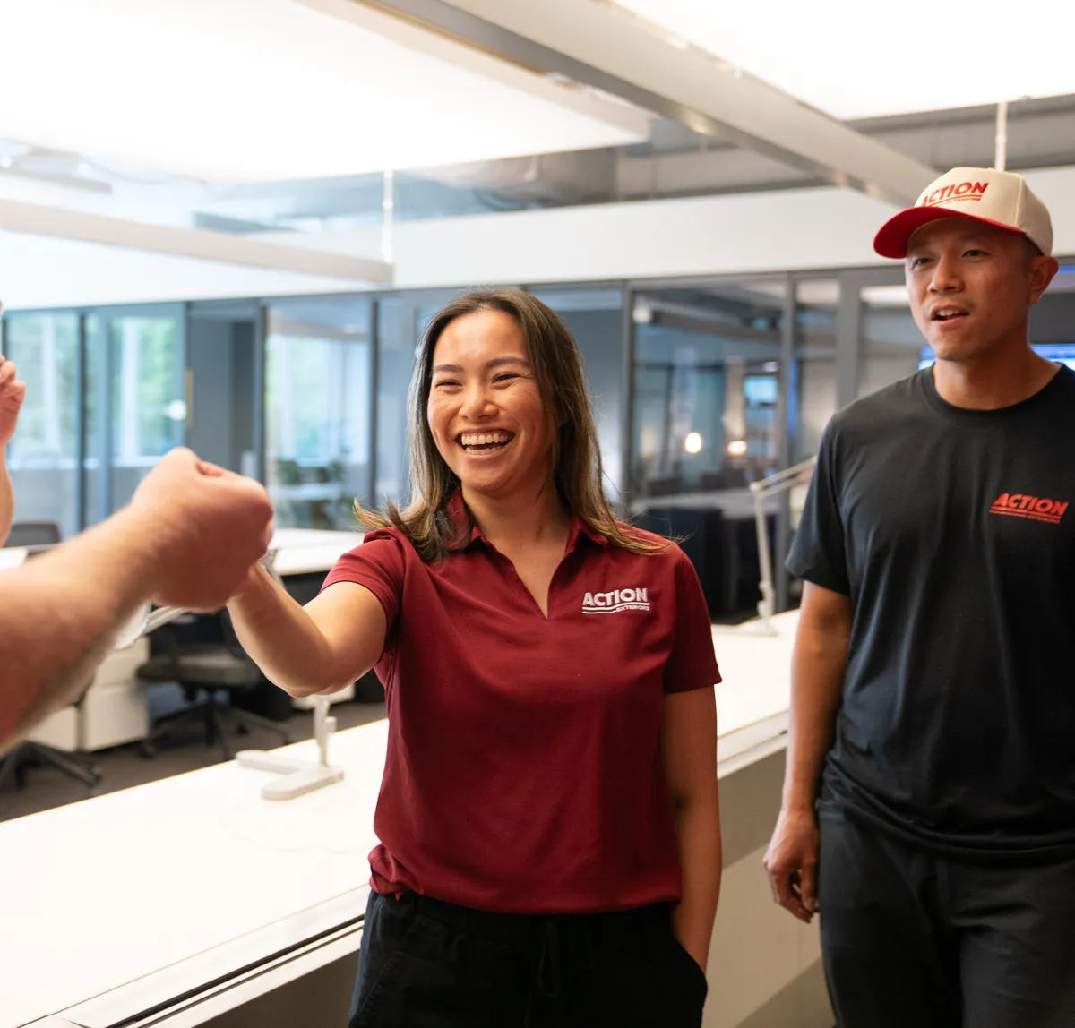 Team member in maroon Action polo laughing during fist bump