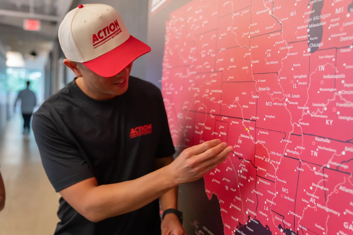Team member in Action hat pointing at large red US map