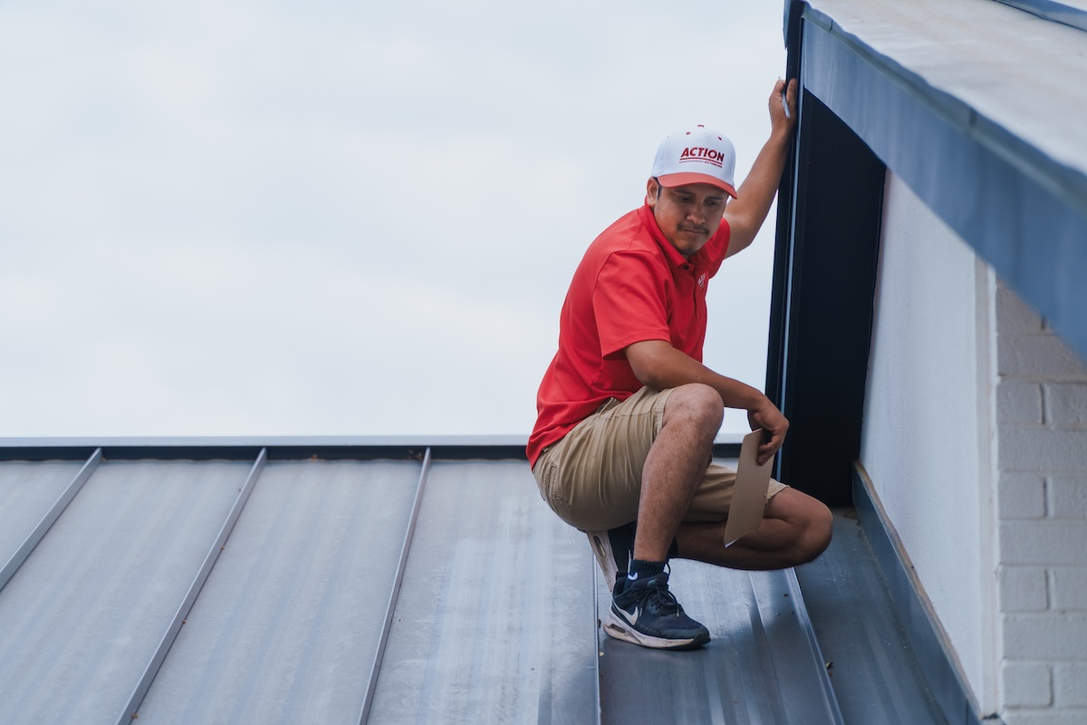 Action Exteriors inspector evaluating a standing-seam metal roof