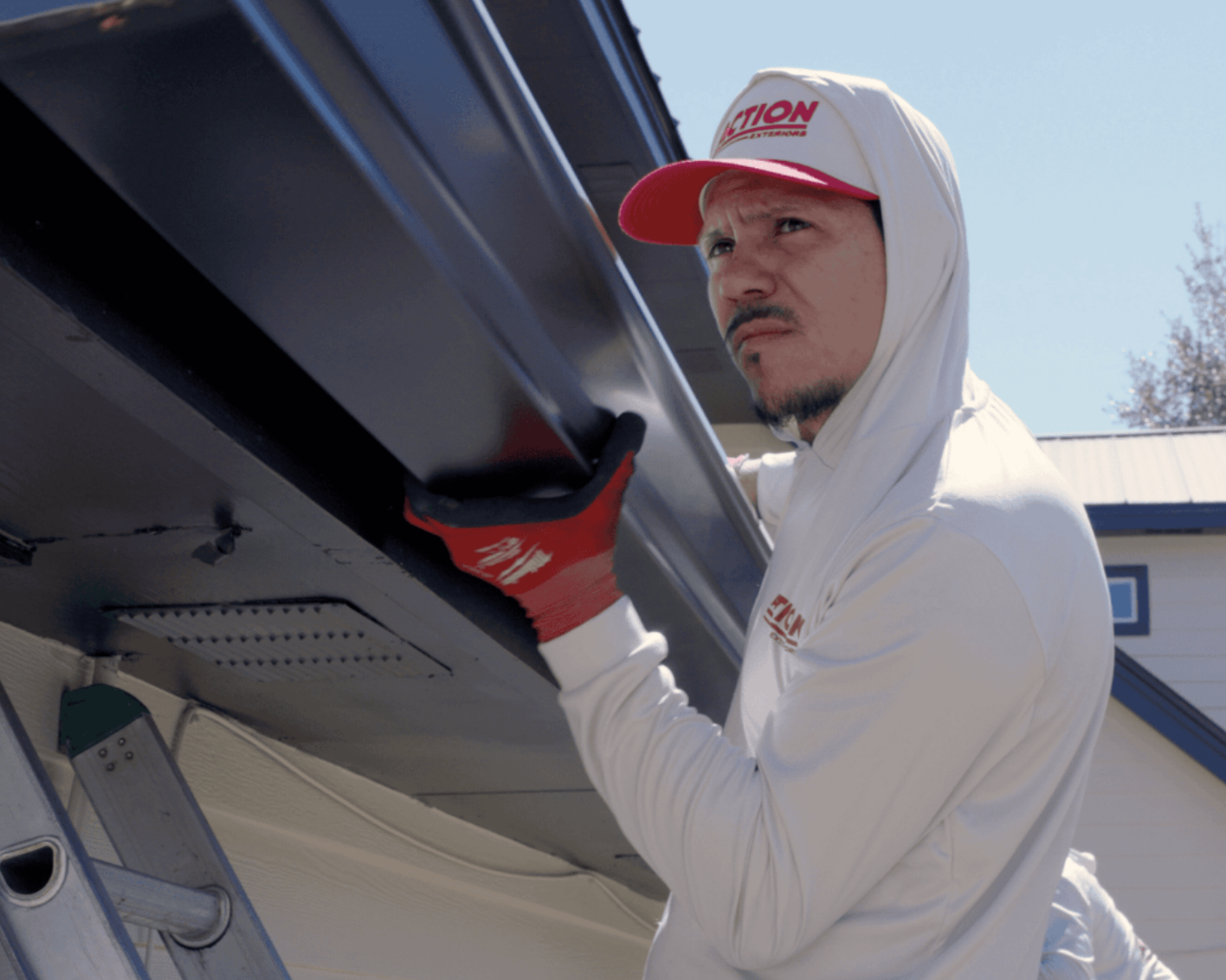 Action Exteriors team member installing gutters on a home