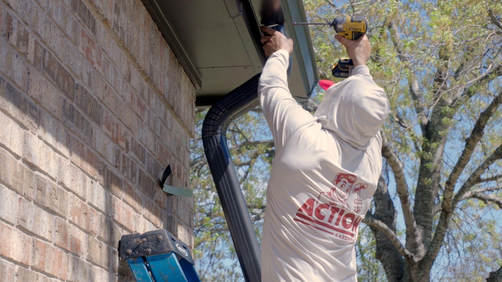 An Action Exteriors Austin employee installing a gutter onto a roof - roof repair services- roof leaks