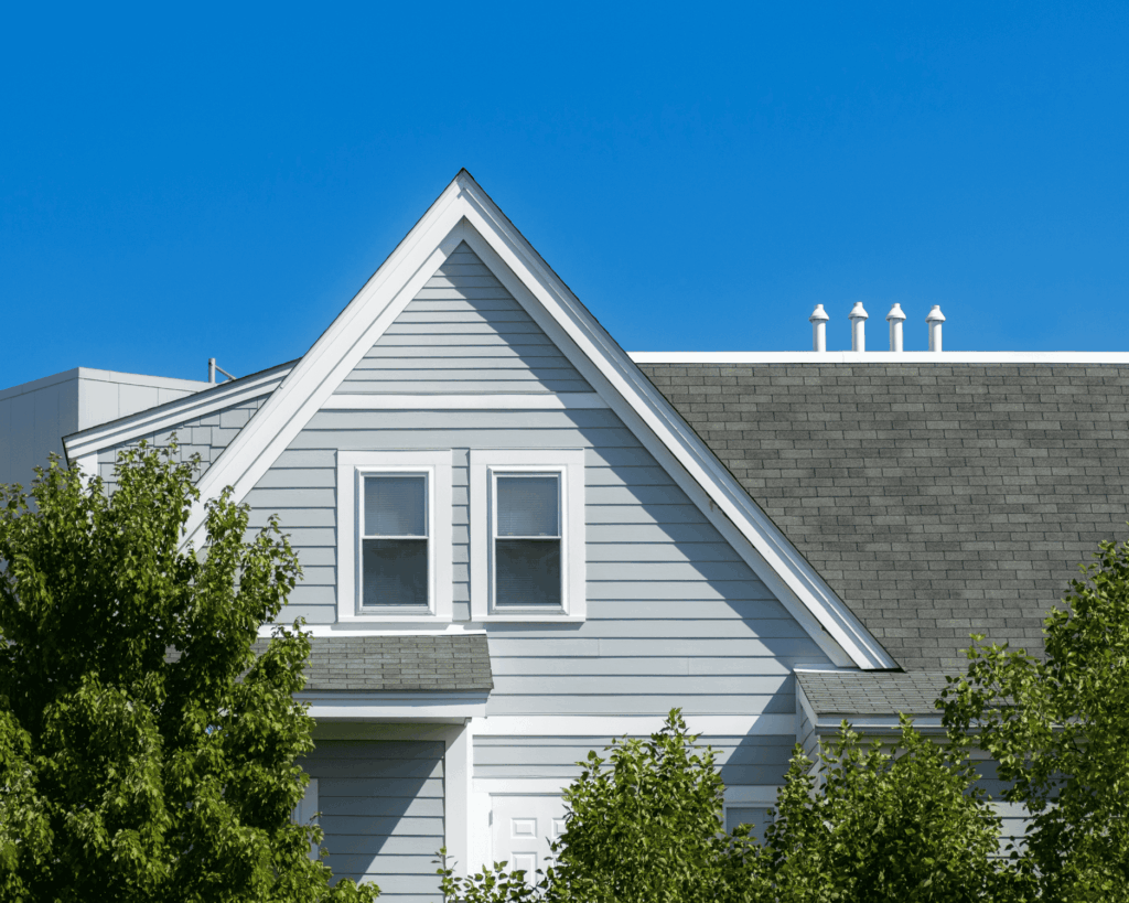 a blue home with siding and white trim and a gray shingled roof installed by a local roofing services company