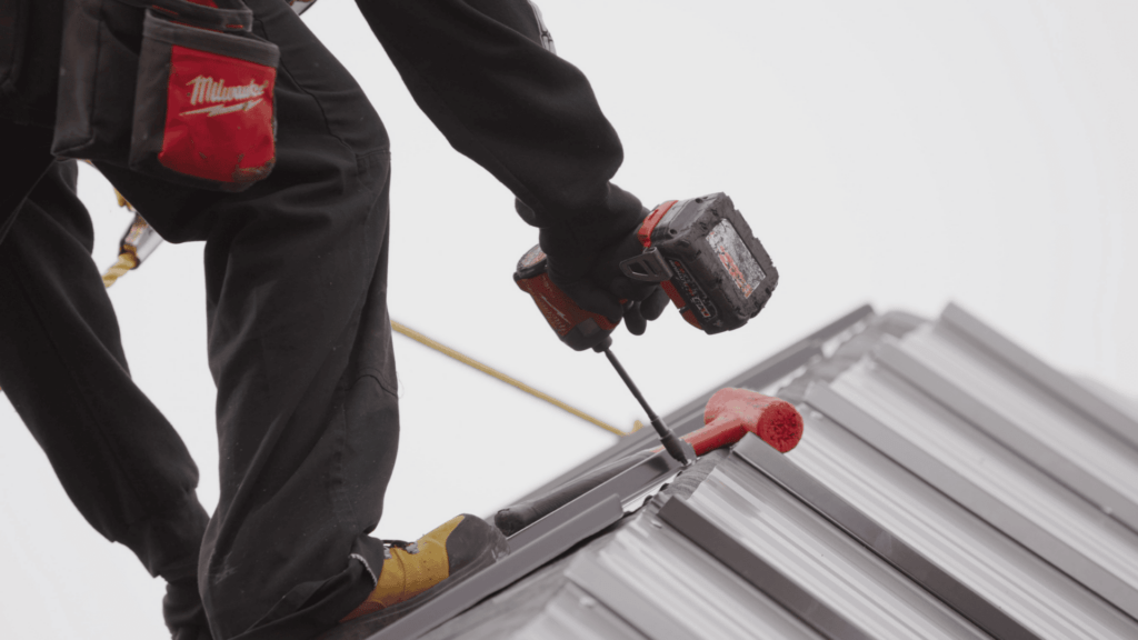 A roofer replacing a commercial metal roof - Action Exteriors