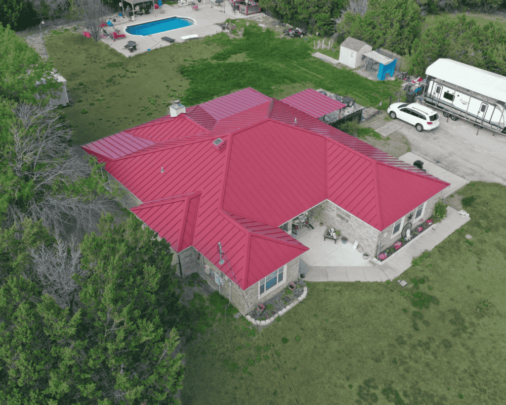 an aerial shot of a home with a red metal roof installed by professional tulsa roofers_action exteriors