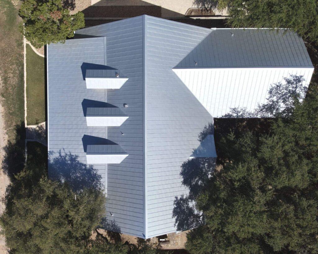 the birds eye view of a commercial building with a newly installed silver metal roof completed by action exteriors tulsa