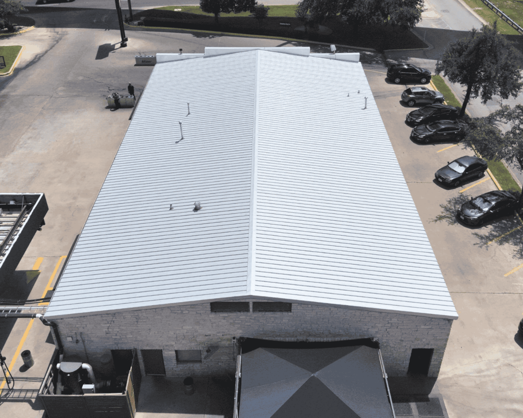 a completed commercial metal roofing project with a silver roof done by action exteriors professional roofers