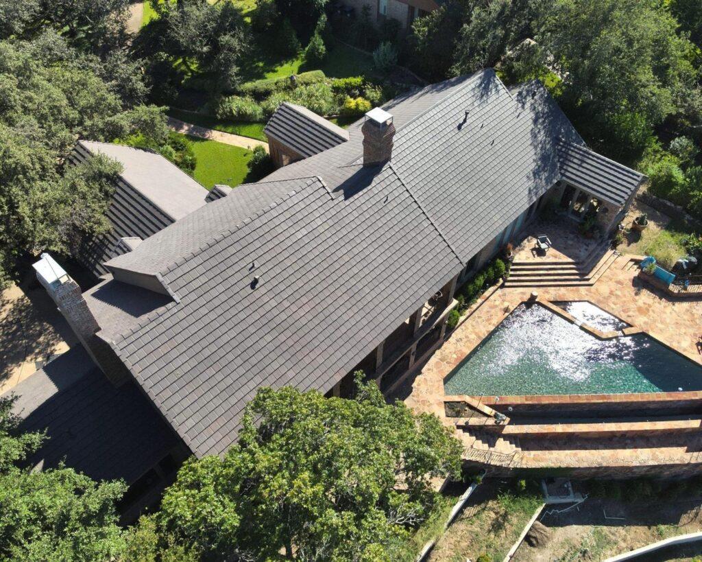 an aerial view of a home with a pool and a new asphalt roof installed by action exteriors professional roofers