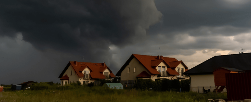 a row of homes with dark storm clouds approaching in the background_action exteriors tulsa. Prevent roof leaks.