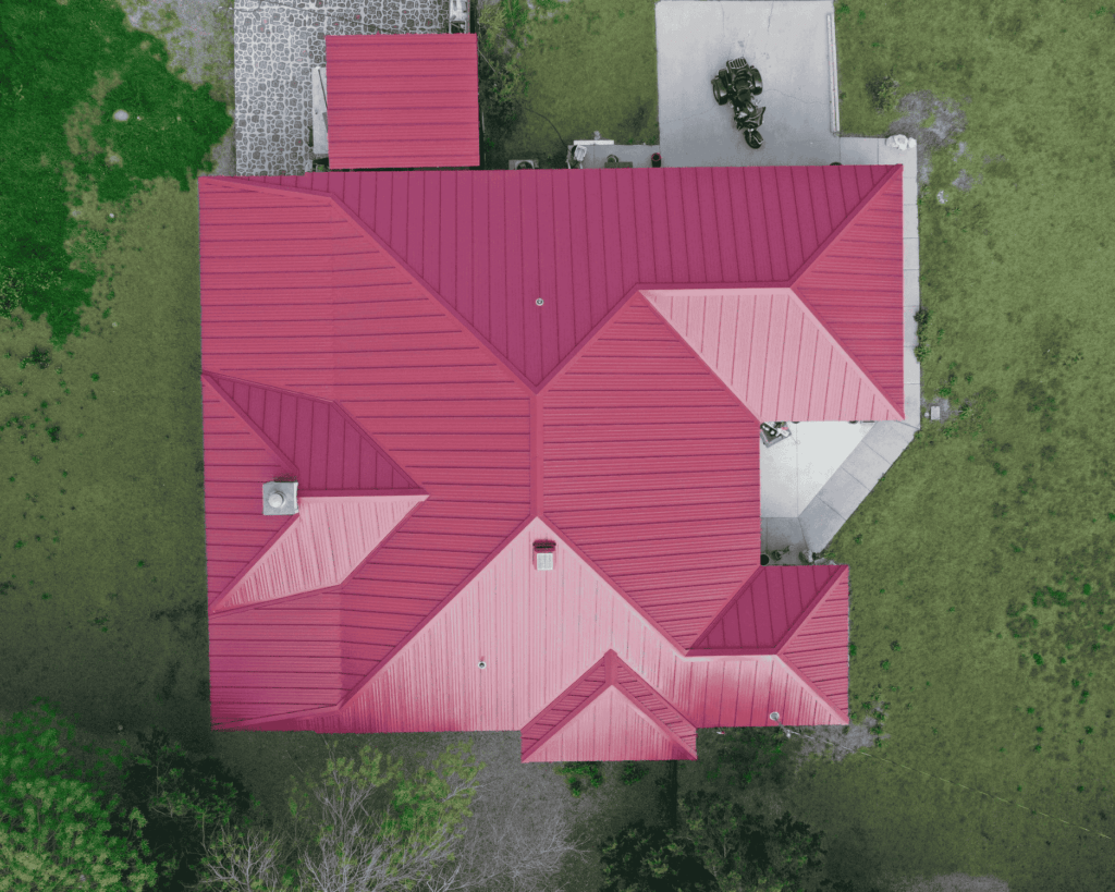 an arial view of a residential home with a red metal roof completed by action exteriors