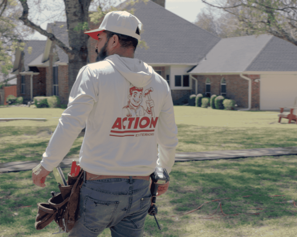an action exteriors professional roofer walking onto a job site wearing action exteriors merch - quality roofer