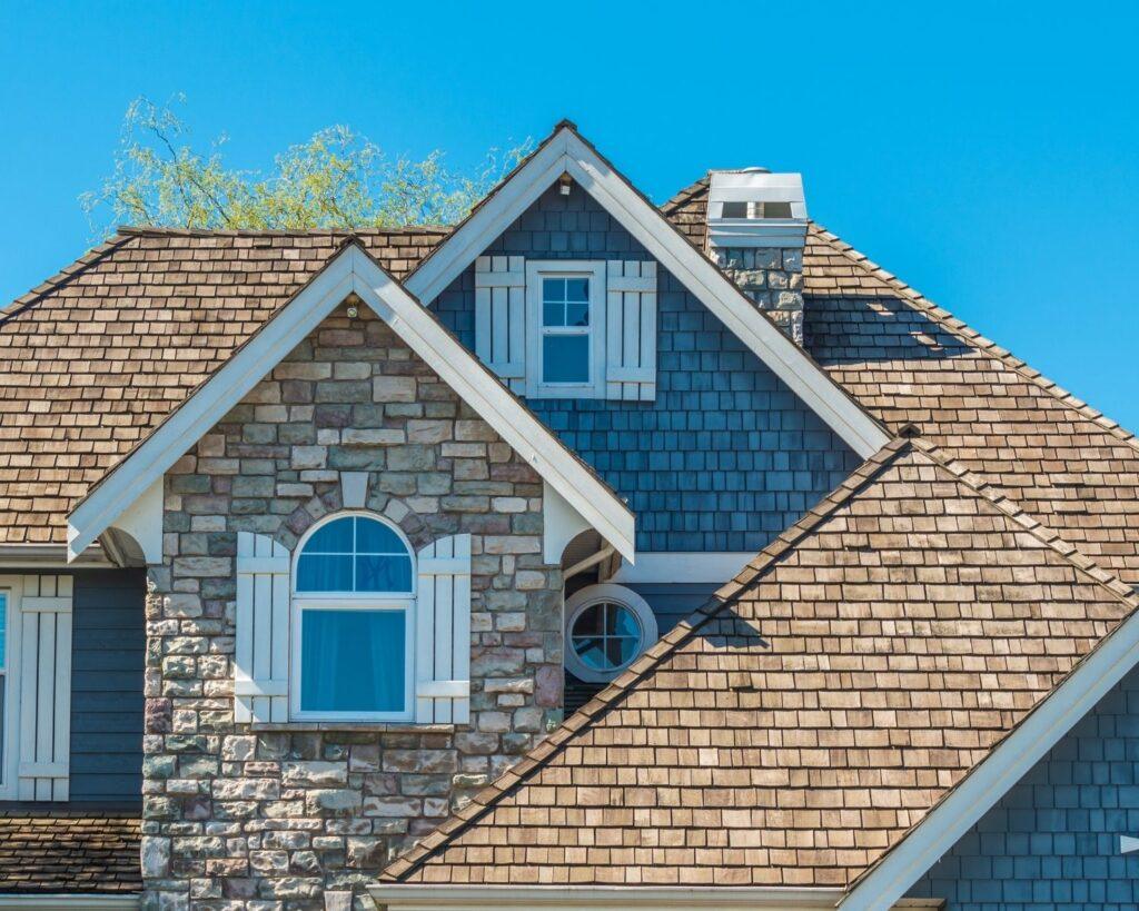 a blue two story home with a roof with brown shingles_action exteriors