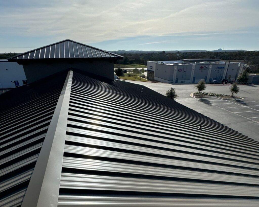 a black metal roof on top of a commercial building installed by action exteriors