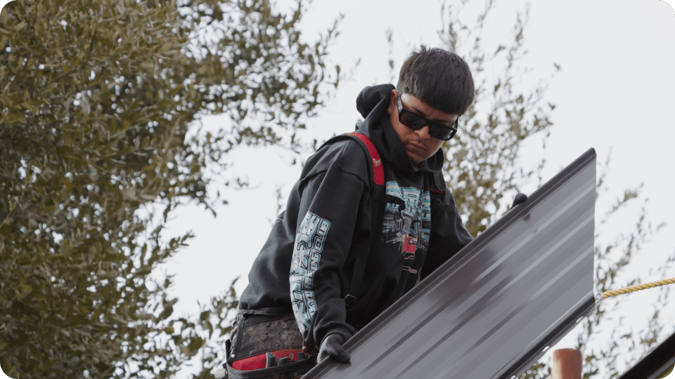A professional roofer carrying a metal roof for installation_action exteriors